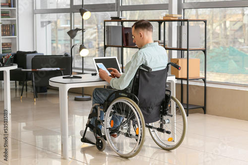 Young man in wheelchair working in office