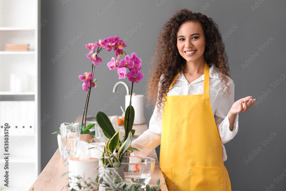 Young woman taking care of her orchid flowers at home - obrazy, fototapety, plakaty 