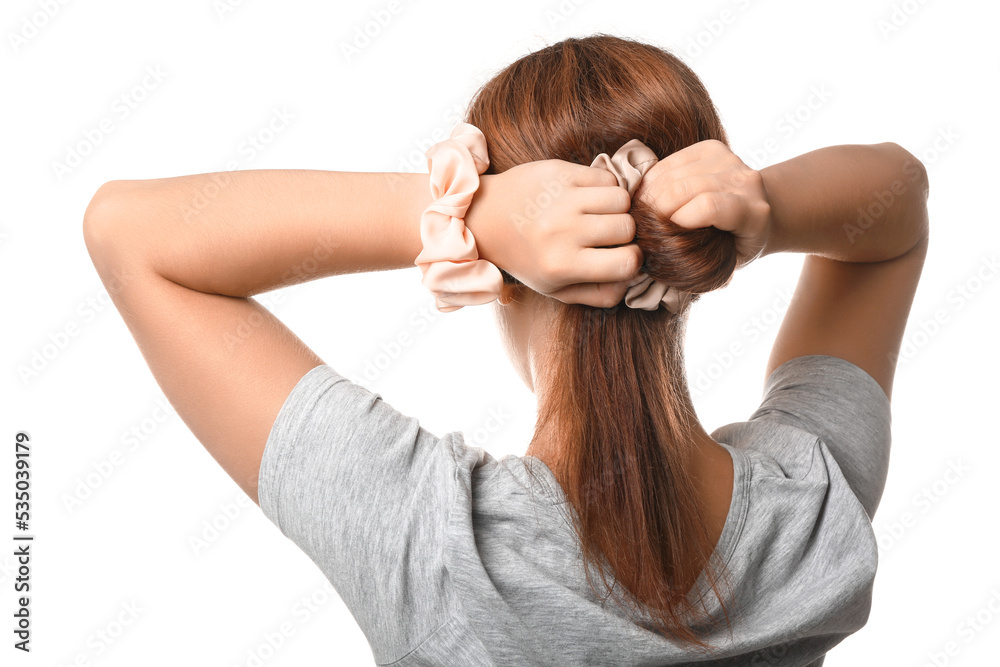 Woman tying hair with silk scrunchy on white background, closeup Woman tying hair with silk scrunchy on white background, closeup