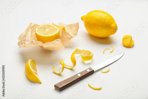 Ripe lemons, peel and knife on white background photo