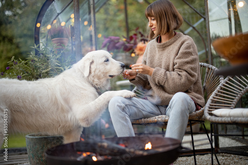 Woman with a dog by the fire at backyard