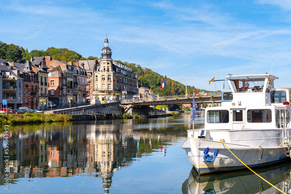 View on riverside promenade of river meuse with sightseeing cruise ship, medieval citiyscape background against blue sky