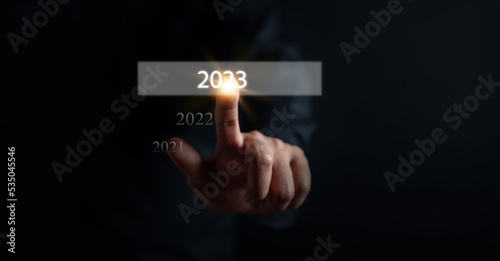 Businessman touching virtual screen on number 2023 for preparation and change to merry Christmas and happy new year concept.