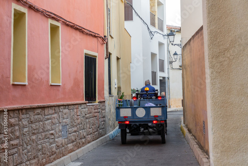 Fototapeta Naklejka Na Ścianę i Meble -  Small tractor with a trailer through the narrow streets of the village