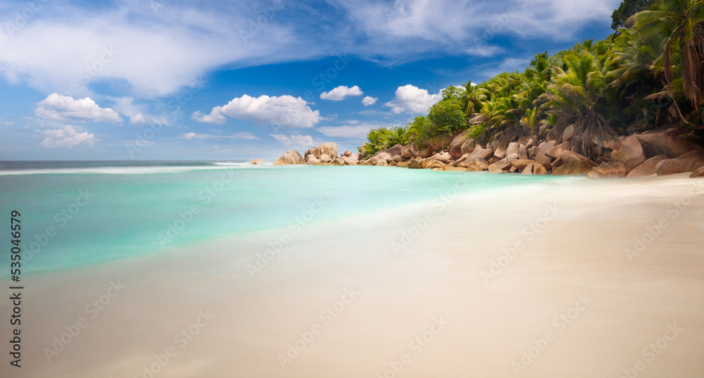 Palm and tropical beach panorama. Anse Lazio beach at Praslin island, Seychelles, long exposure, vintage toning. Palm and tropical beach, vacation travel concept Palm and tropical beach panorama. Anse Lazio beach at Praslin island, Seychelles, long exposure, vintage toning. Palm and tropical beach, vacation travel concept