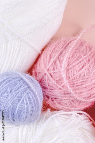 Threads for knitting in white, gray and pink colors on a pink background