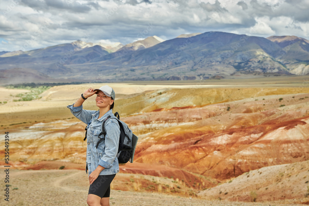 Fototapeta premium woman tourist in jeans jacket stands against backdrop of landscape on summer day. Sights of Russia, Siberia and Altai Republic, mars field. Tourism, travel and adventure. Kosh-agach, Chagan-Uzun
