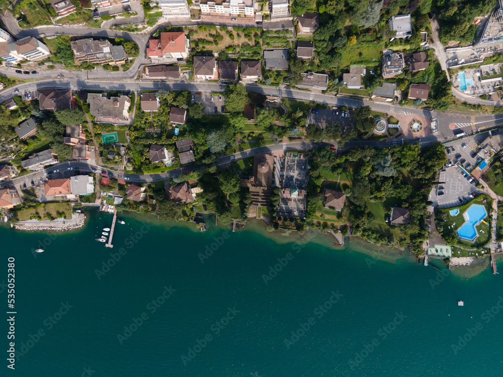 Campione d'Italia coast line during summer time with the Lugano lake view and swimming pools and boats and roads and houses