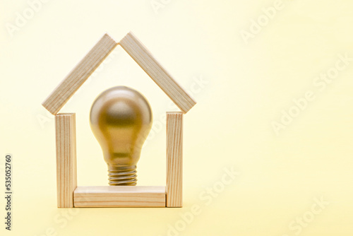 house of wooden blocks and lightbulb. Real estate market, innovation, new project, idea concept on a yellow background