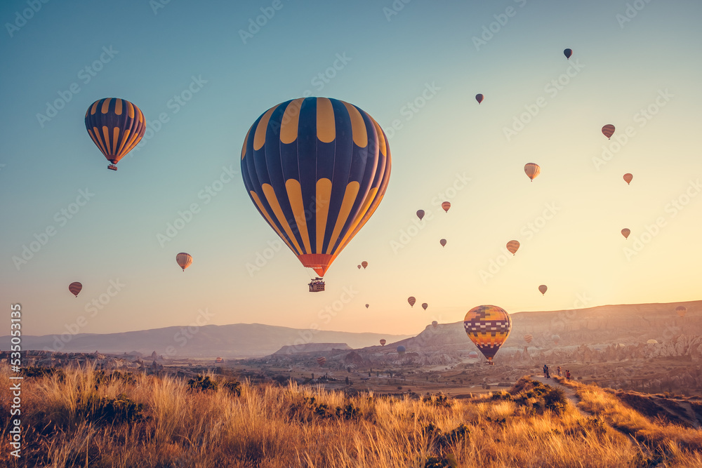 Obraz premium Amazing sunrise with colorful hot air balloons over spectacular Cappadocia valley. Background for your travel concept. Natural summer scenery, morning sun rise watching