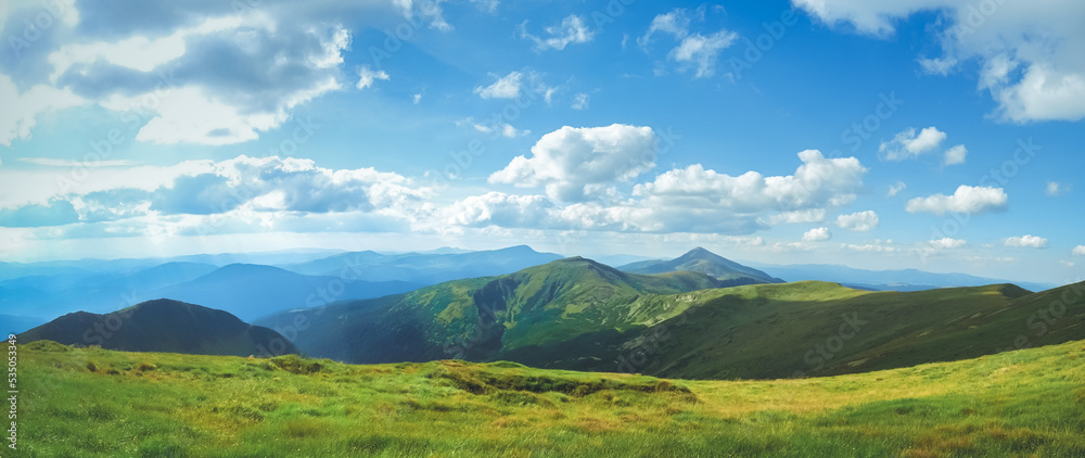 Amazing alps panorama green meadow and mountain range. Blue sky and clouds in sunny day. Beautiful natural summer scenery. Alpine highlands nature landscape. Travel adventure concept image. Copy space