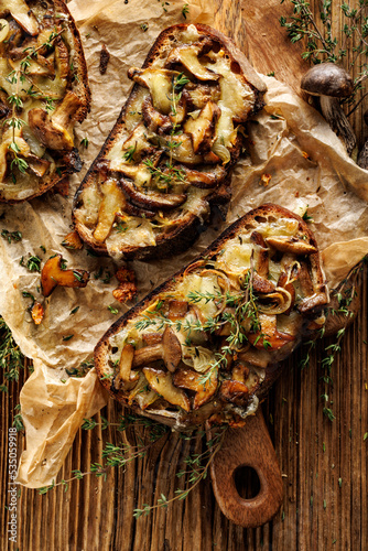 Sourdough bread toasts with mushrooms, mozzarella cheese and thyme on a wooden table, top view