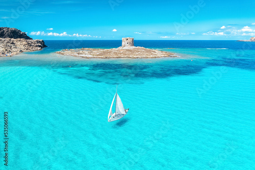 Beautiful seascape with white sailing yacht in summer on a sunny day aerial view. Popular beach La Pelosa, Sardinia, Italy. Travel, hobby concept photo