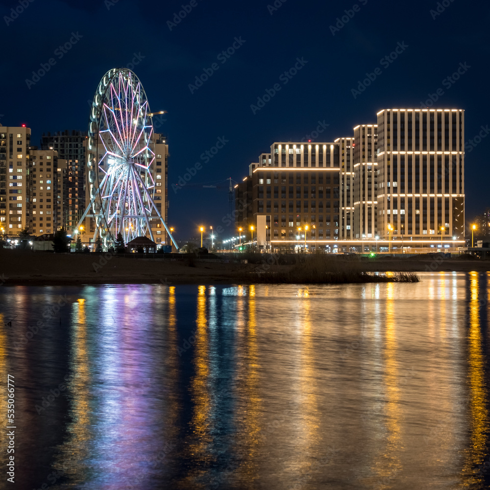 Panorama night city Kazan. View of the new quarters of new buildings and the Ferris wheel in the evening illumination