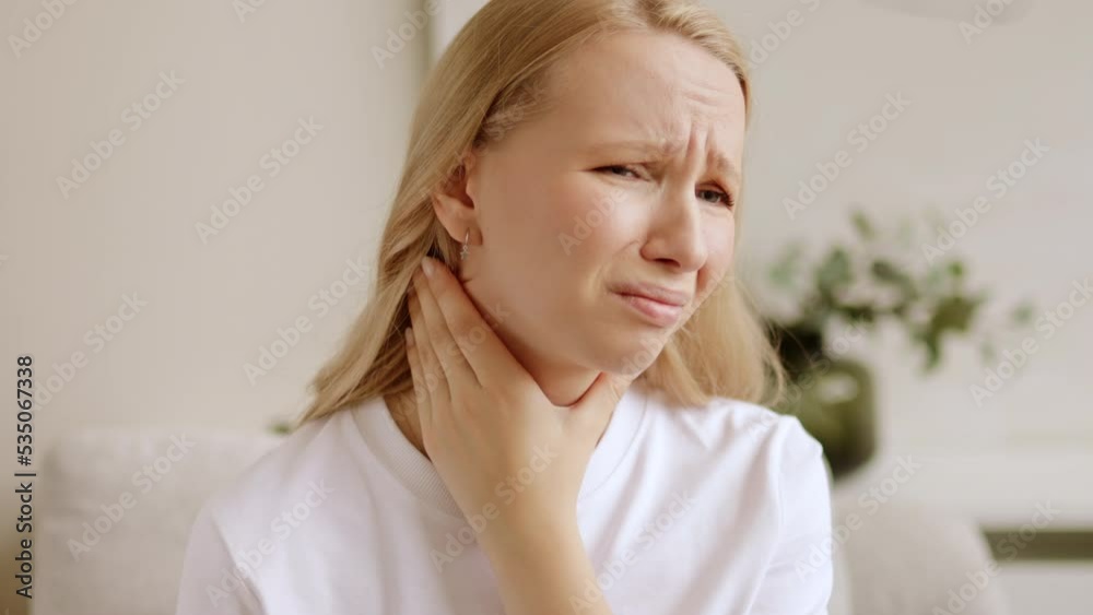 Unhealthy woman touches her sore throat has difficulty swallowing. Painful neck and frowning, thyroid disorders. Angina or tonsils inflammation. Unhealthy woman touches her sore throat has difficulty swallowing. Painful neck and frowning, thyroid disorders. Angina or tonsils inflammation.