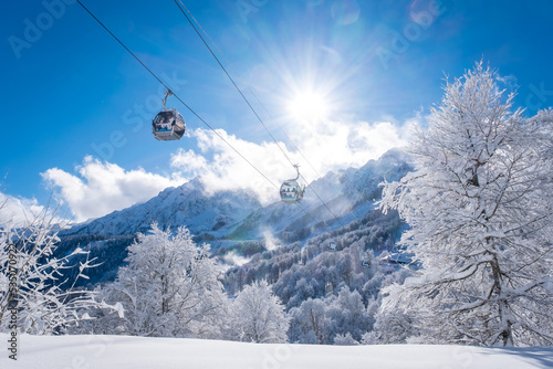 Winter Mountain landscape at the Rosa Khutor ski resort in Sochi, Russia. Trees in hoarfrost against a beautiful morning sky in a frosty morning. Snow cannons sprinkle snow on the slopes photo