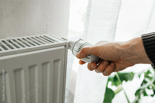 Fotografía A man regulates the temperature on the radiator at home