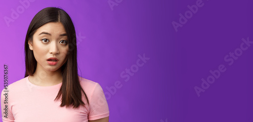 Close-up confused shocked cute young silly asian girl hear strange accusations open mouth gasping stunned, look speechless and puzzled, did not expect such behaviour, purple background