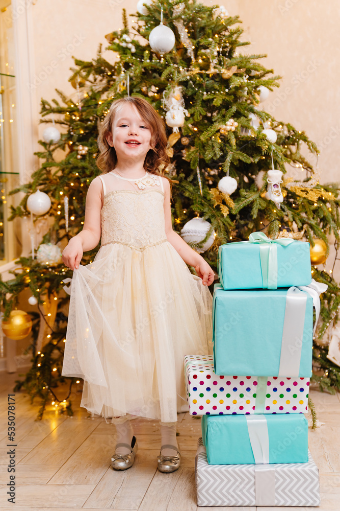little girl with gifts by Christmas tree. tradition giving gifts little girl with gifts by Christmas tree. tradition giving gifts
