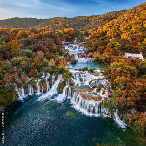 Krka, Croatia - Aerial panoramic view of the famous Krka Waterfalls in Krka National Park on a bright autumn morning with colorful autumn foliage and blue sky