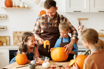 Happy family mother, father and kids  to remove pulp from from pumpkin while carving jack o lantern with family