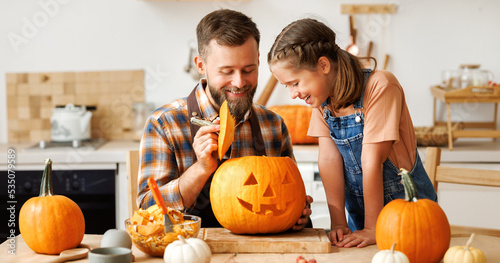 Foto Daughter and dad making Jack-o-Lantern together at home, carving Halloween pumpk