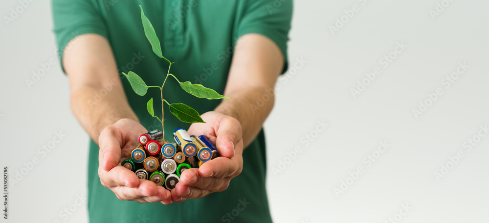Leaf grows from a batteries in hand. Green energy a symbol of clean energy resources. Concentration of waste recycling and environmental pollution. banner with copy space