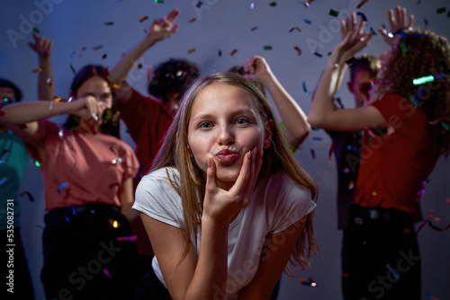 Teenage girl near friends dancing and having fun