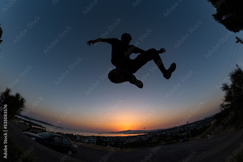 Young male jump with high energy with a low angle shot and colorful sunset sky at background Young male jump with high energy with a low angle shot and colorful sunset sky at background