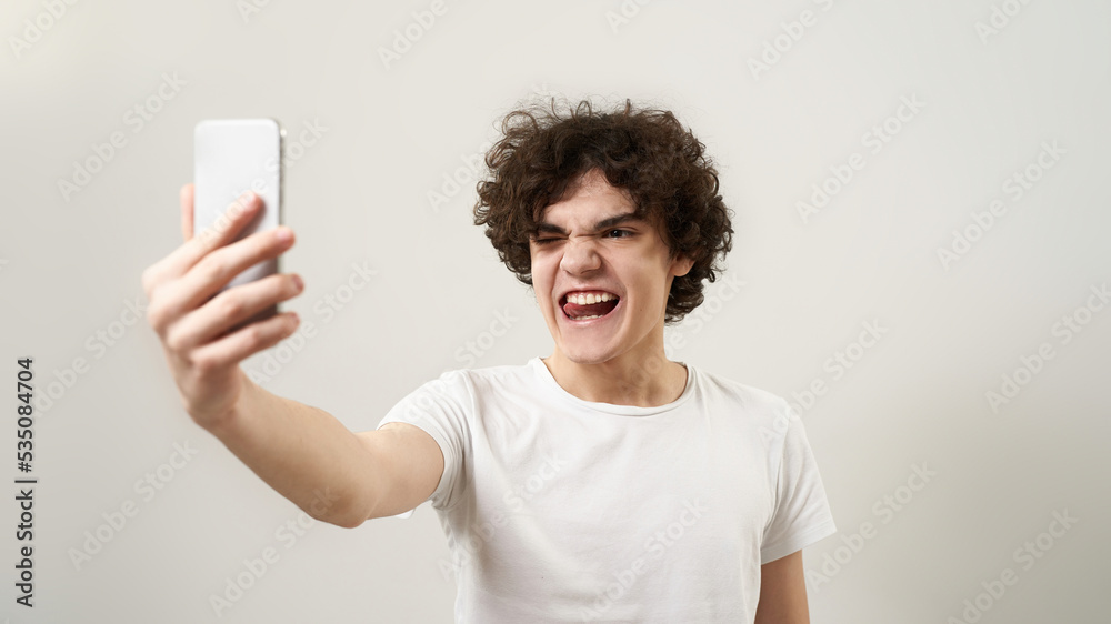Boy wink and stick out tongue while take selfie