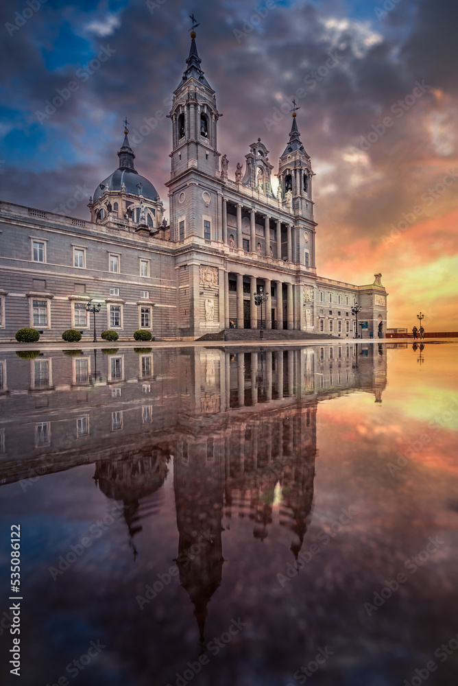 Madrid Almudena Cathedral with reflection on water after rain and colorful sunset sky and clouds on background