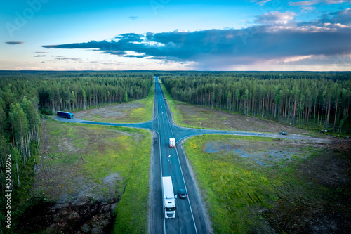 Asphalt road under the clouds. Top view of the road through the green summer forest