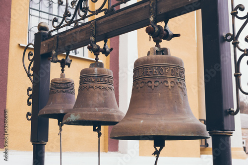 Three big iron copper or lettuce churh bells hanging on forged cross-bar