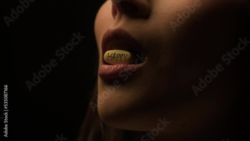Hard time. A woman swallows a pill of happiness in the dark.