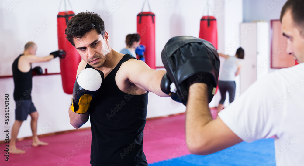 Two male athletes in sportswear exercising boxing sparring in gym