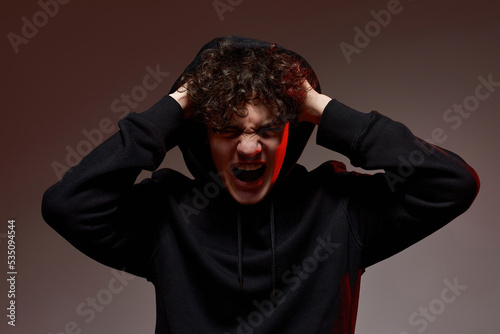 Irritated boy with open mouth hold head and scream