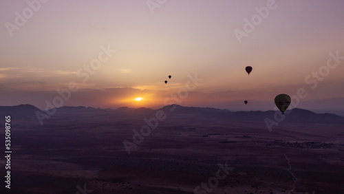 hot air balloon flying over the Moroccan desert and the atlas mountains at sunrise