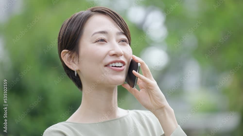 スローモーション スマホで話すミドル女性(新緑・屋外) スローモーション スマホで話すミドル女性(新緑・屋外)