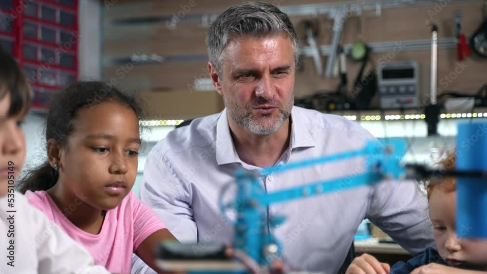Close up of enthusiastic teacher and diverse children watching on working robotic electric machine they made at robotics engineering class. School science classroom of futuristic technologies. STEM Close up of enthusiastic teacher and diverse children watching on working robotic electric machine they made at robotics engineering class. School science classroom of futuristic technologies. STEM