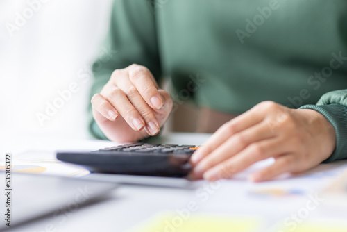 Close up of businesswoman Accounting using calculating income-expenditure and analyzing real estate investment data report Financial and tax systems concept.	