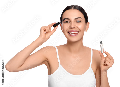 Young woman applying oil onto eyelashes on white background