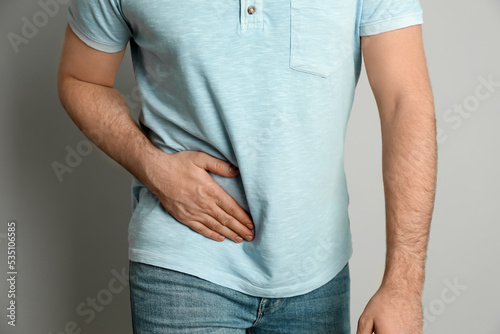 Man suffering from acute appendicitis on light grey background, closeup photo