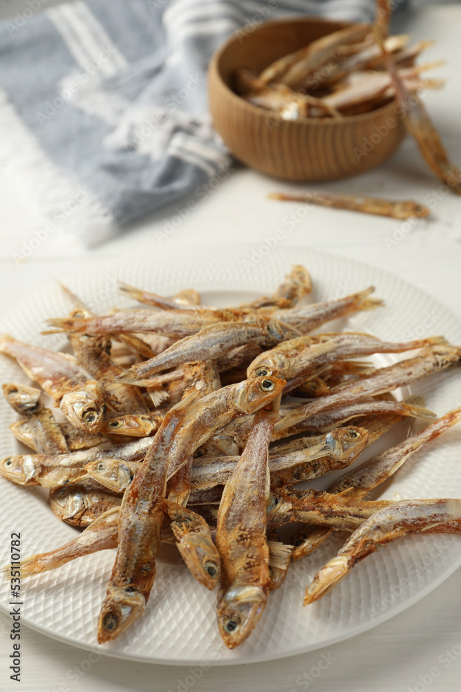 Plate with tasty dried anchovies on white table, closeup Plate with tasty dried anchovies on white table, closeup