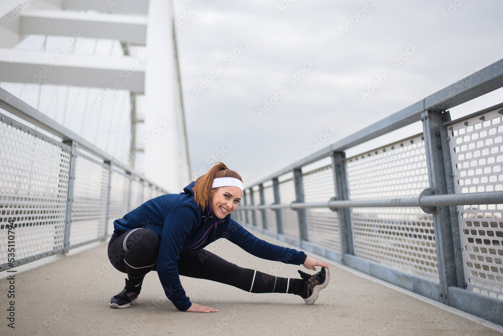 Young smiling sport woman doing stretching exercise on the bridge in spring Young smiling sport woman doing stretching exercise on the bridge in spring