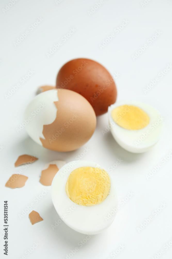 Hard boiled eggs and pieces of shell on white background Hard boiled eggs and pieces of shell on white background