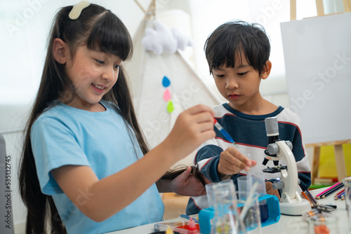 Two little scientists making chemical test with toy microscope in living room