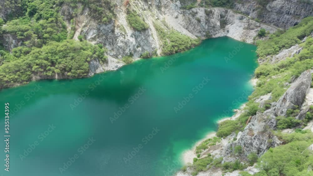 Grand Canyon Chonburi. Trucks dig coal mining of ore with black grunge ground in quarry with mountain hills. Nature landscape background in factory industry. Environment. Aerial footage b roll 4k.