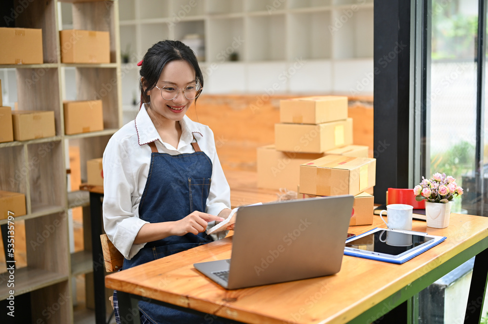 Successful Asian female small online business owner working in her packing room Successful Asian female small online business owner working in her packing room