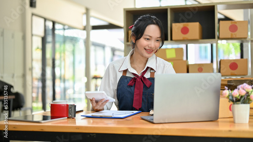 Beautiful Asian female small online business owner working at her desk
