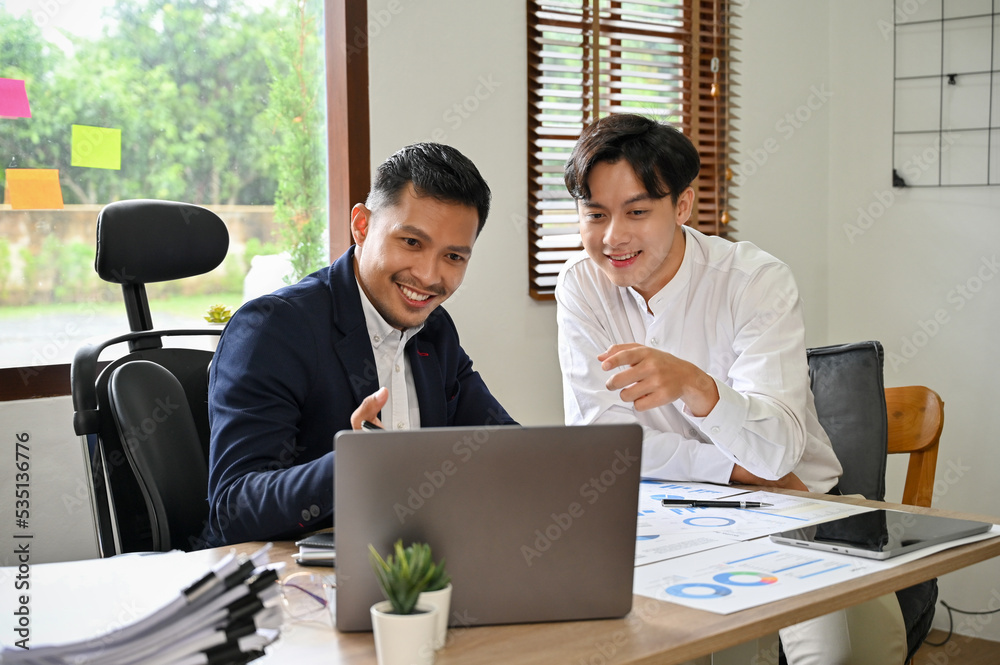 Two Asian businessmen colleagues working, checking their project on a laptop together. Two Asian businessmen colleagues working, checking their project on a laptop together.